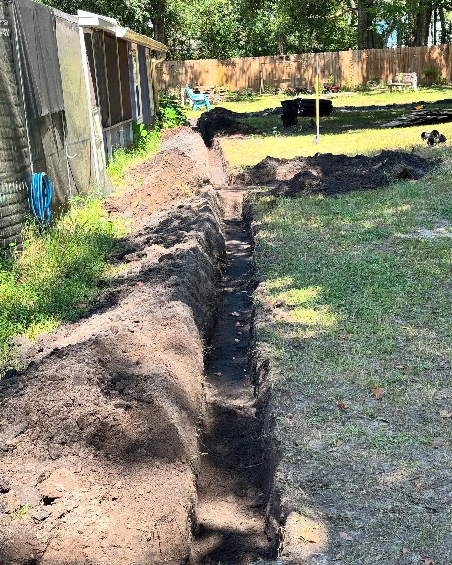 Long drainage trench excavated through a backyard lawn